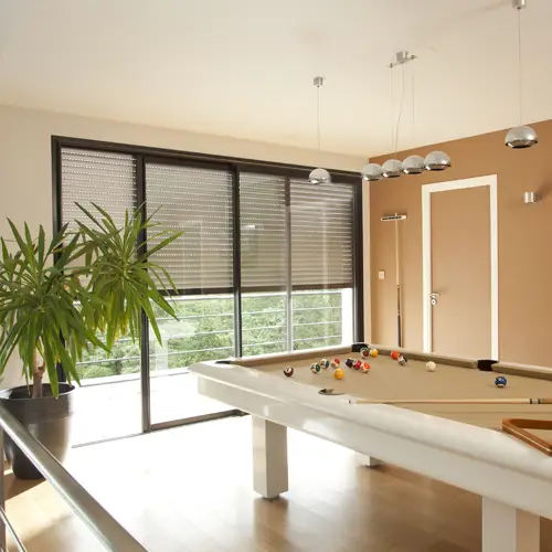 woonkamer met pooltafel en elektrische raamdecoratie