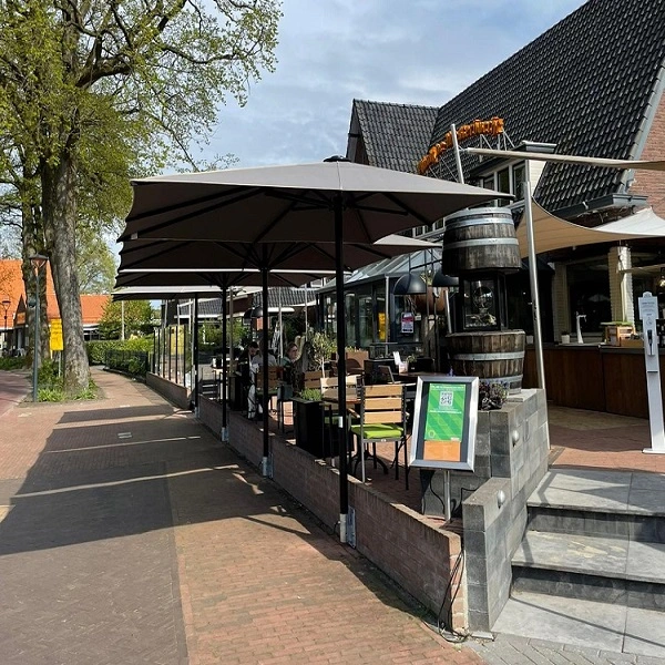 Terras met grote parasols bij horecagelegenheid aan een straat