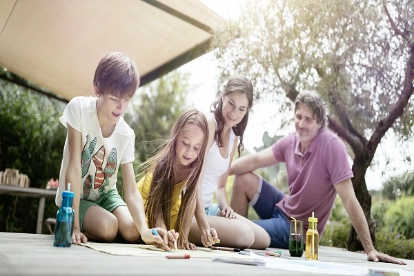 Familie geniet van een zonnige dag onder een knikarmscherm Familie geniet van een zonnige dag onder een knikarmscherm