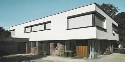 Huis met witte gevel en geïntegreerde rolluiken bij de ingang en ramen Huis met witte gevel en geïntegreerde rolluiken bij de ingang en ramen