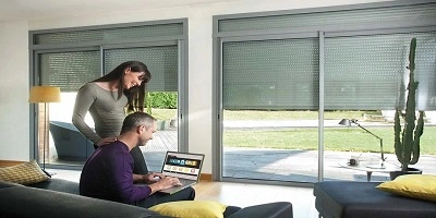 Stel gebruikt laptop in woonkamer met rolluiken met bediening Stel gebruikt laptop in woonkamer met rolluiken met bediening