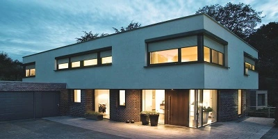 Verlicht modern huis in de avond met rolluiken deels gesloten voor privacy Verlicht modern huis in de avond met rolluiken deels gesloten voor privacy