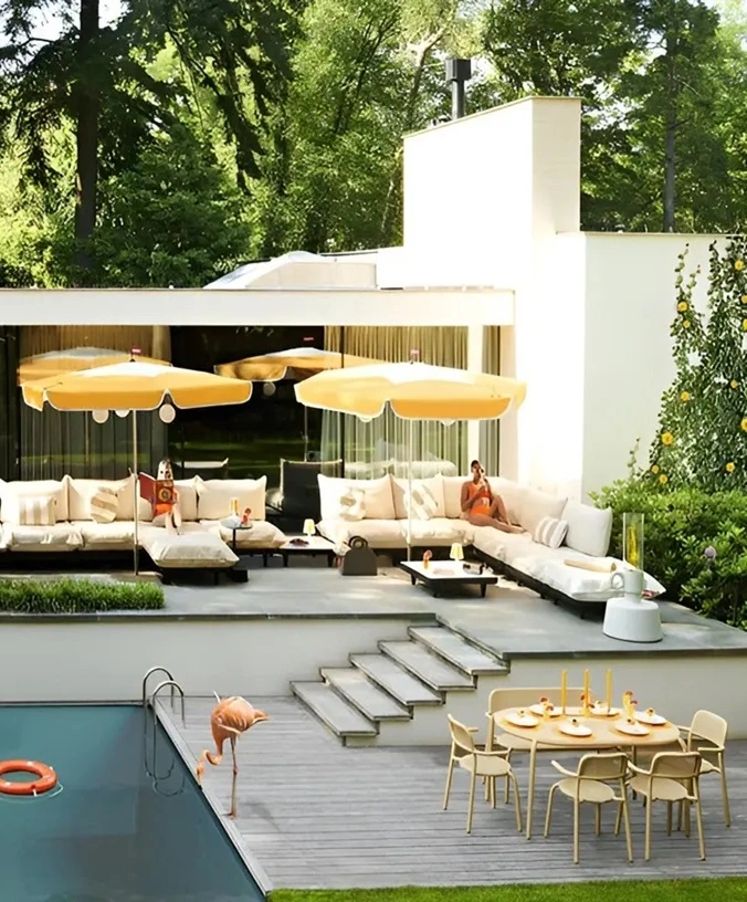 Buitenruimte met grote lounge bank, gele parasols, en een eettafel Buitenruimte met grote lounge bank, gele parasols, en een eettafel