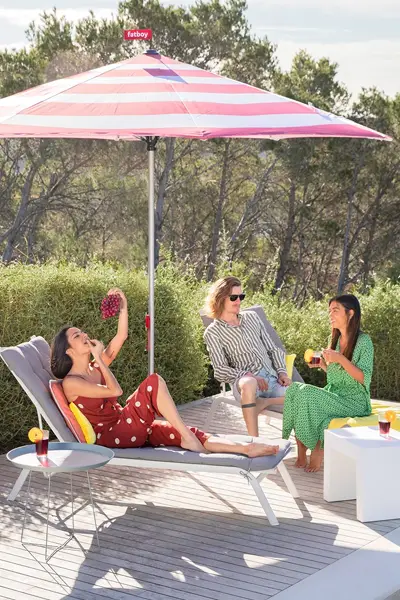 Vrienden ontspannen onder een gestreepte Fatboy parasol op een terras Vrienden ontspannen onder een gestreepte Fatboy parasol op een terras