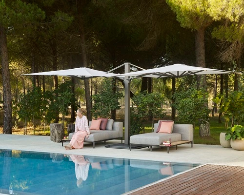 Vrouw zittend op een grijze loungebank bij een zwembad Vrouw zittend op een grijze loungebank bij een zwembad