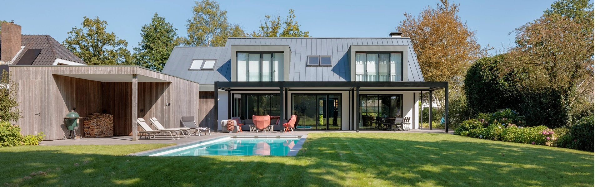 Woning met zwembad en vouwdak, omgeven door een groene tuin