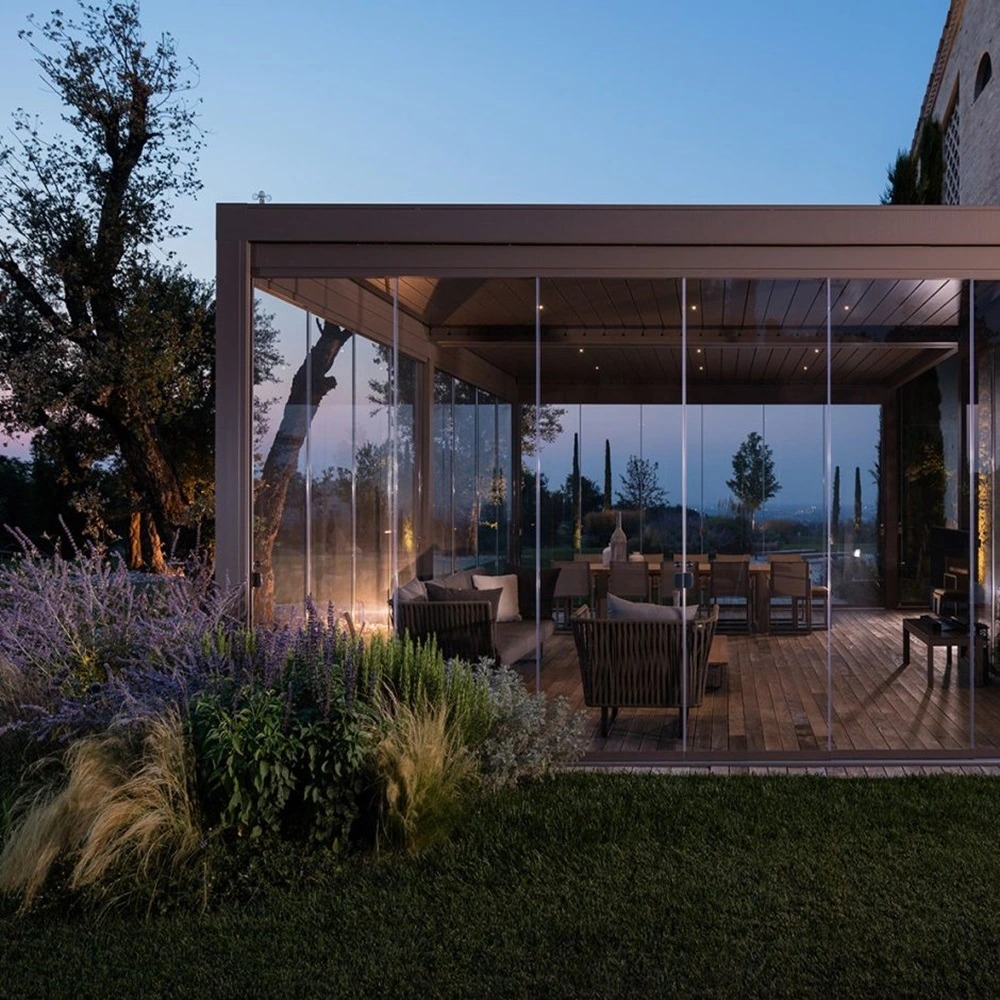 Lamellendak Brera in een tuin met glazen wanden en sfeerverlichting bij schemering