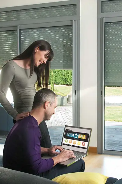 Man en vrouw bedienen motor zonwering via een laptop Man en vrouw bedienen motor zonwering via een laptop