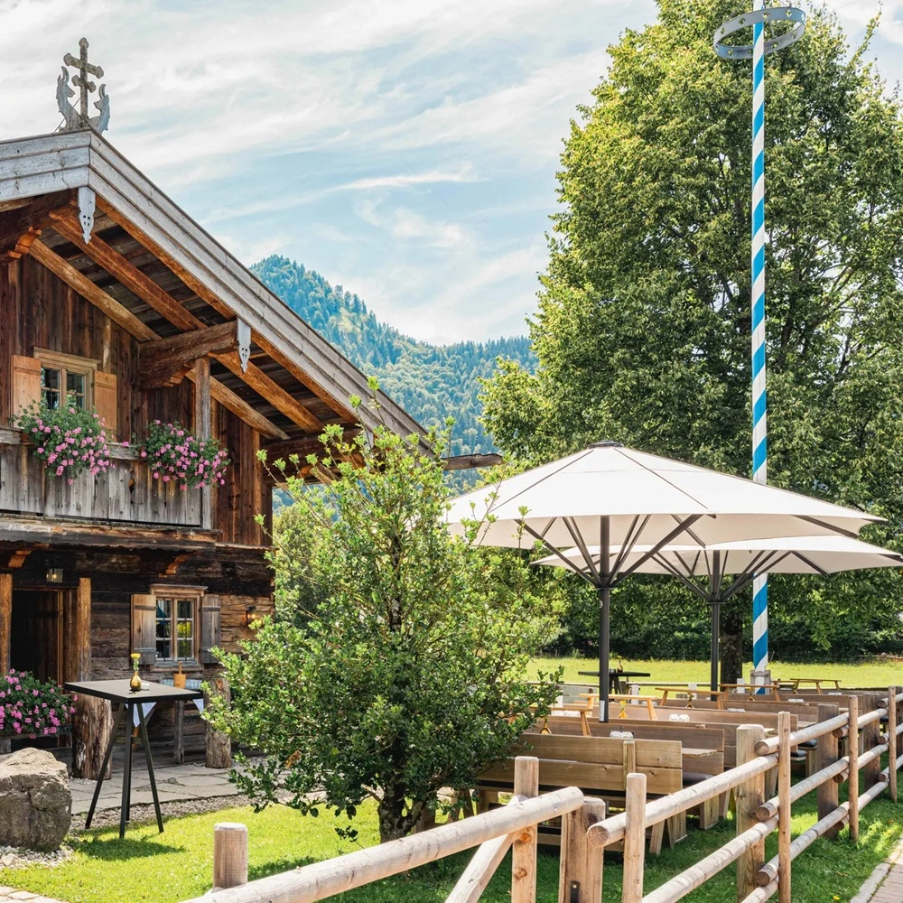 Parasol Schatello naast houten huis in bergachtige omgeving
