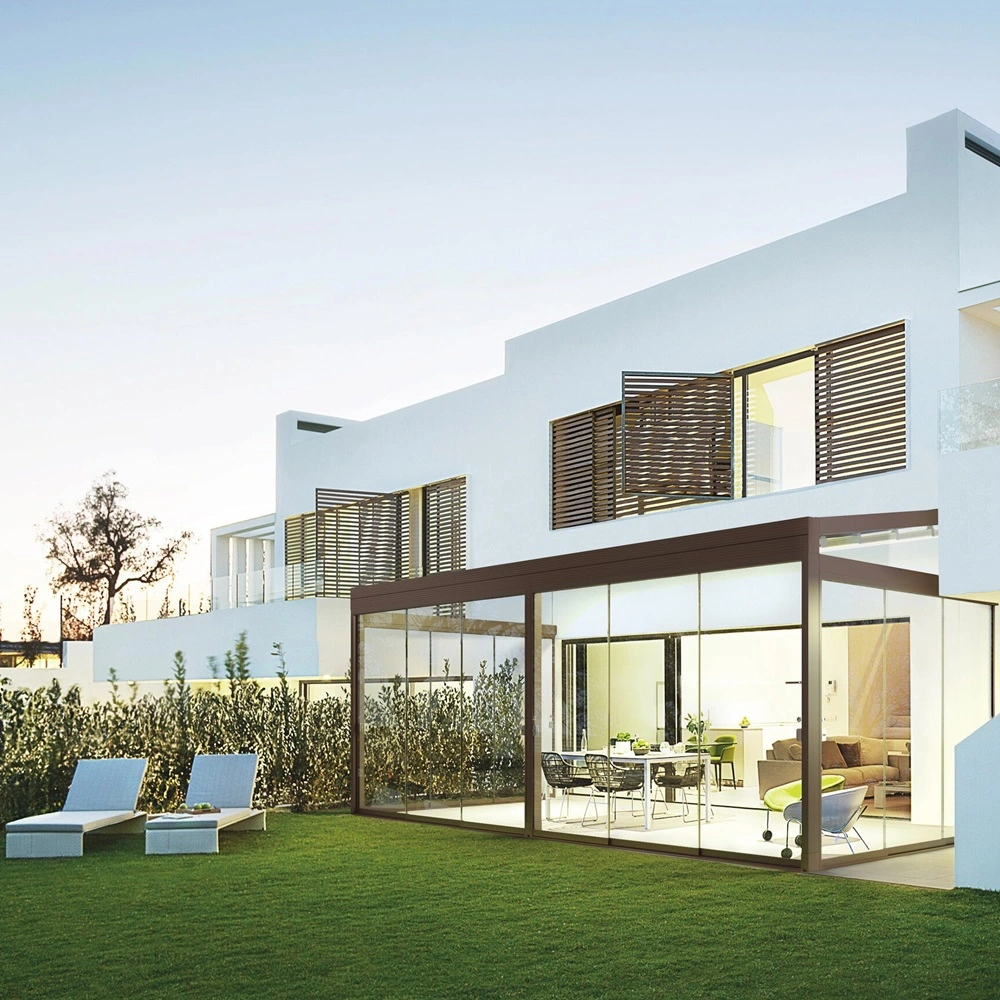 Schuine overkapping Quadra met glazen wanden aan een witte woning in de avond Schuine overkapping Quadra met glazen wanden aan een witte woning in de avond