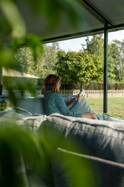 Versuz overkapping met doek, vrouw zittend op bank in tuin Versuz overkapping met doek, vrouw zittend op bank in tuin