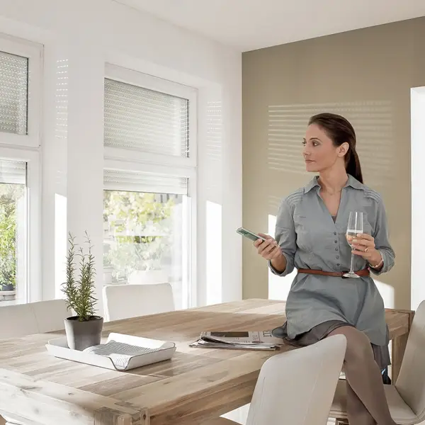 Vrouw bedient zonweringssysteem met afstandsbediening Vrouw bedient motor zonweringssysteem met afstandsbediening