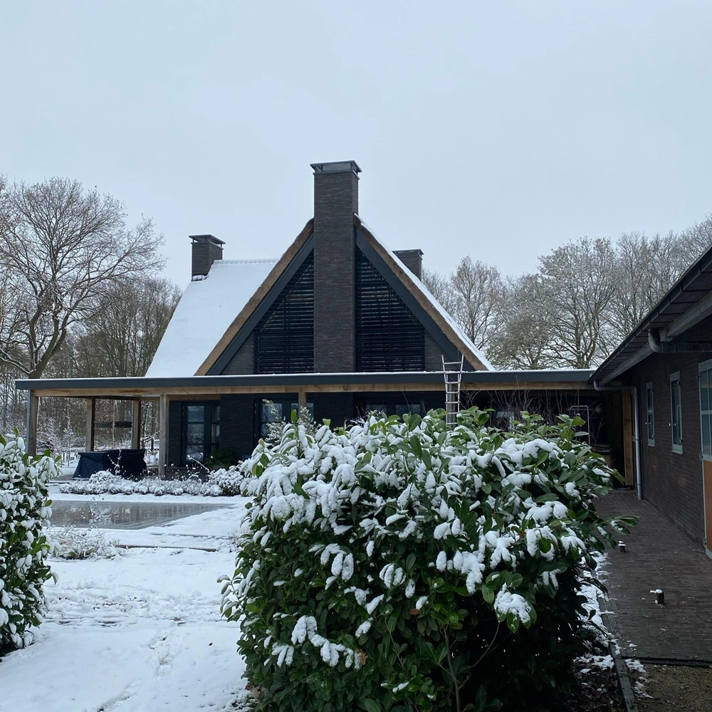 Achteraanzicht van huis met louvre zonwering en besneeuwde tuin Achteraanzicht van huis met louvre zonwering en besneeuwde tuin