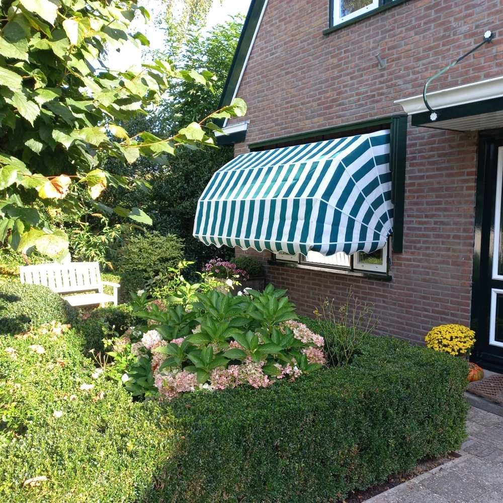 Aluminium markies met groene en witte strepen aan de gevel van een huis met groene voordeur