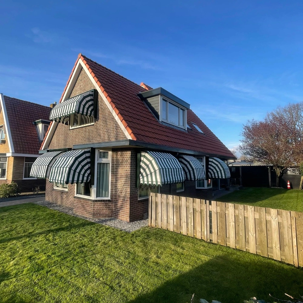 Bakstenen huis met groen-wit gestreepte aluminium markiezen rondom de ramen