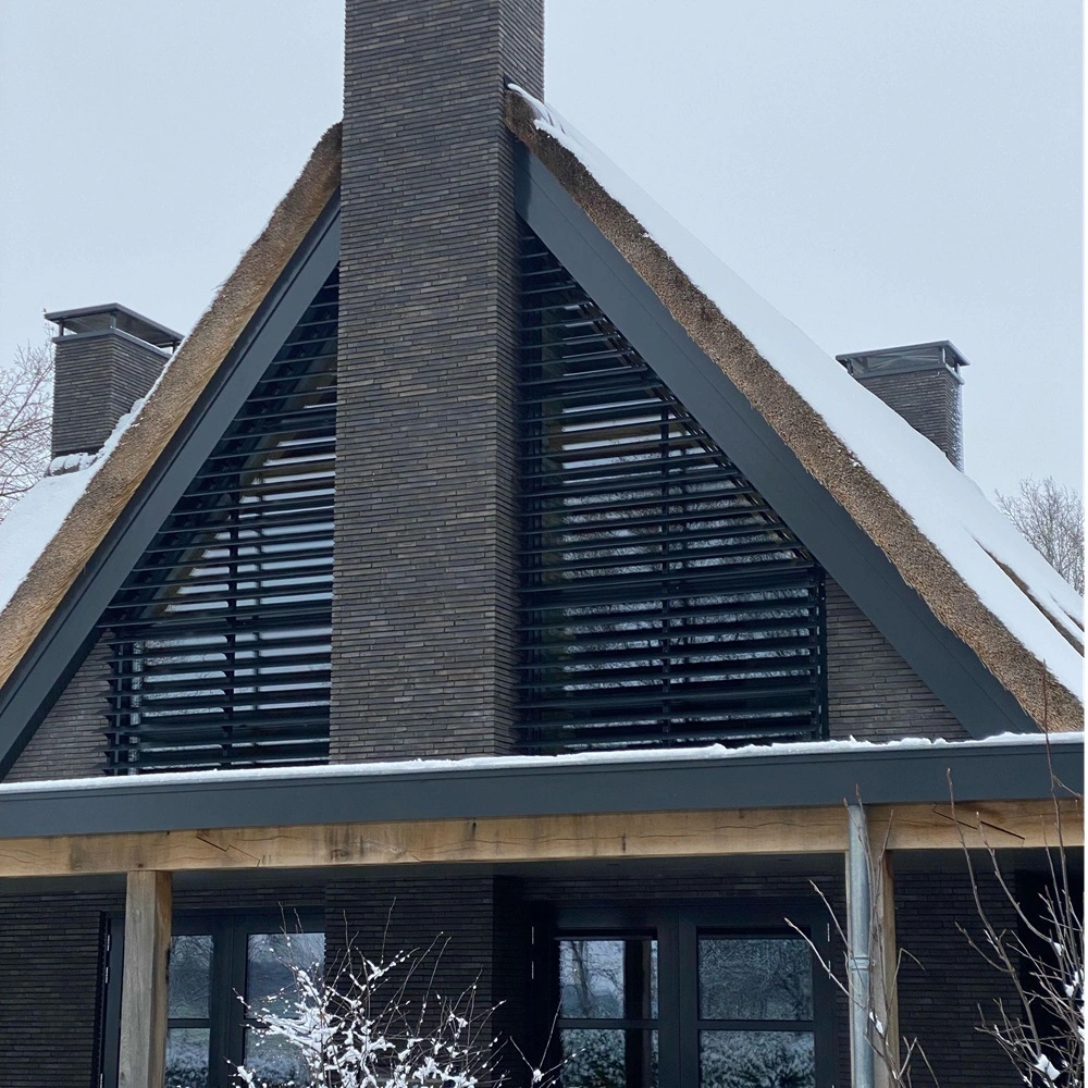 Close-up van louvre zonwering op gevel met rieten dak en sneeuw