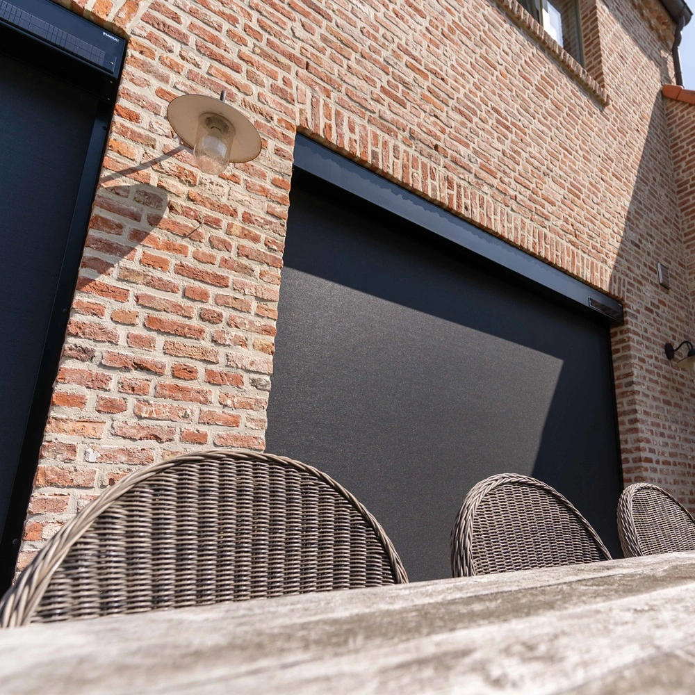 Cool screen Solar zonwering op bakstenen gevel met rieten tuinstoelen