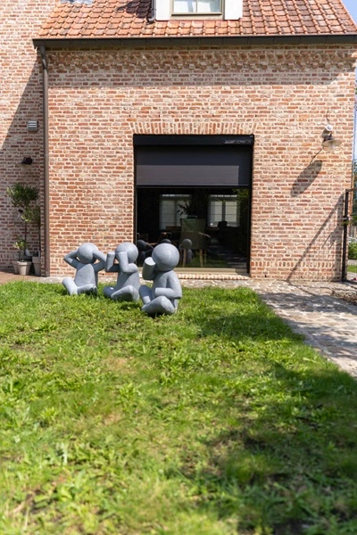 Cool screen Solar zonwering op bakstenen gevel van woning met beeldjes in tuin Cool screen Solar zonwering op bakstenen gevel van woning met beeldjes in tuin