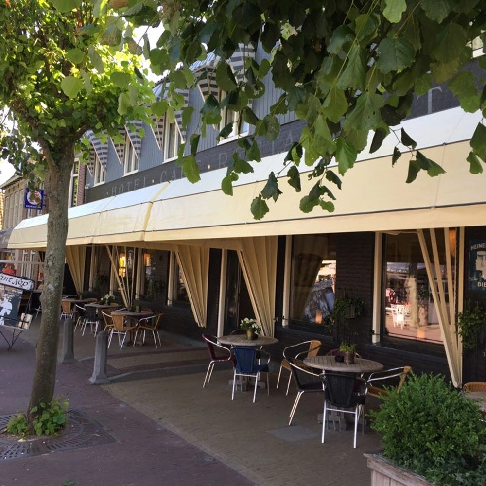 Gele horeca markies bedekt het terras van een cafe-restaurant met tafels en stoelen