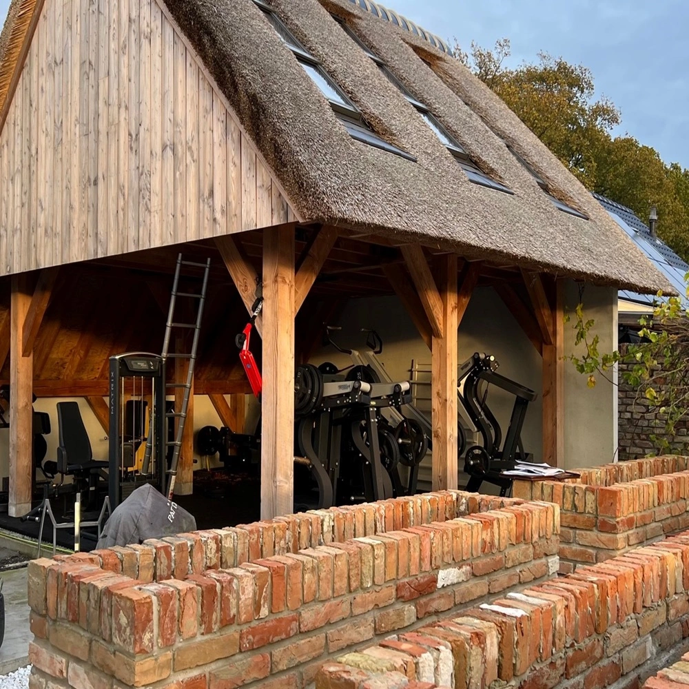 Houten bijgebouw met fitnessapparatuur en W17 Easy glazen schuifwand