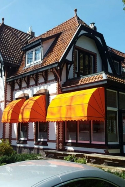 Houten markies in oranje boven ramen van een historisch pand Houten markies in oranje boven ramen van een historisch pand