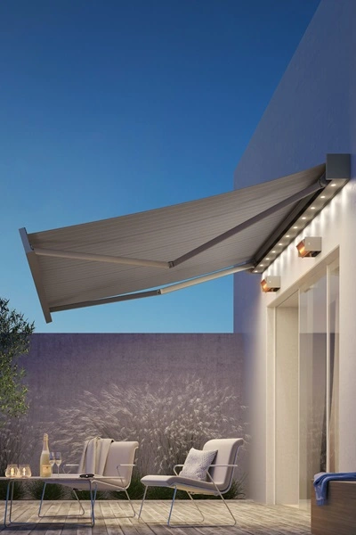 Kubata zonnescherm met LED-verlichting boven terras in avondlicht Kubata zonnescherm met LED-verlichting boven terras in avondlicht