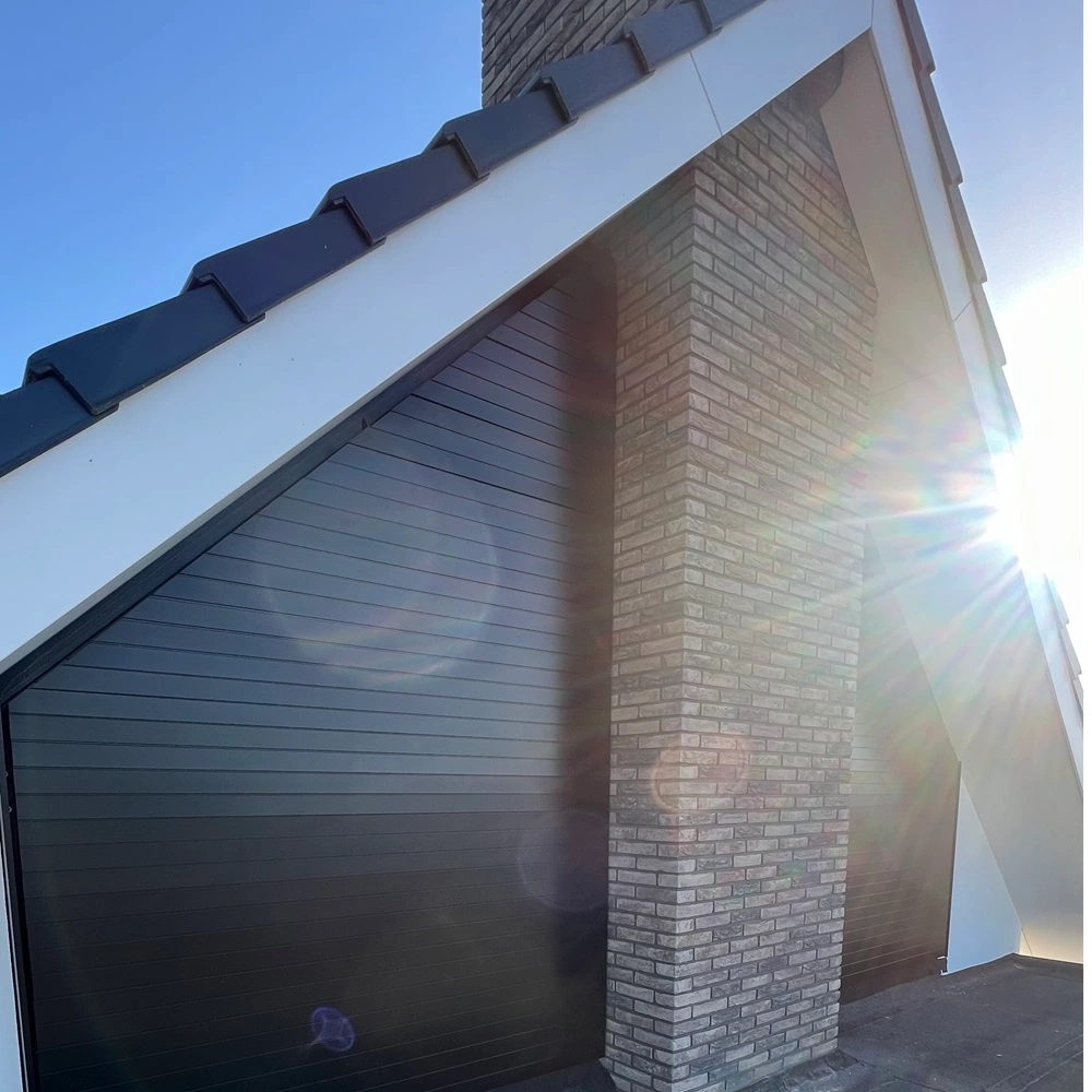 Louvre zonwering naast schoorsteen op puntdak van huis met zonnestralen in beeld