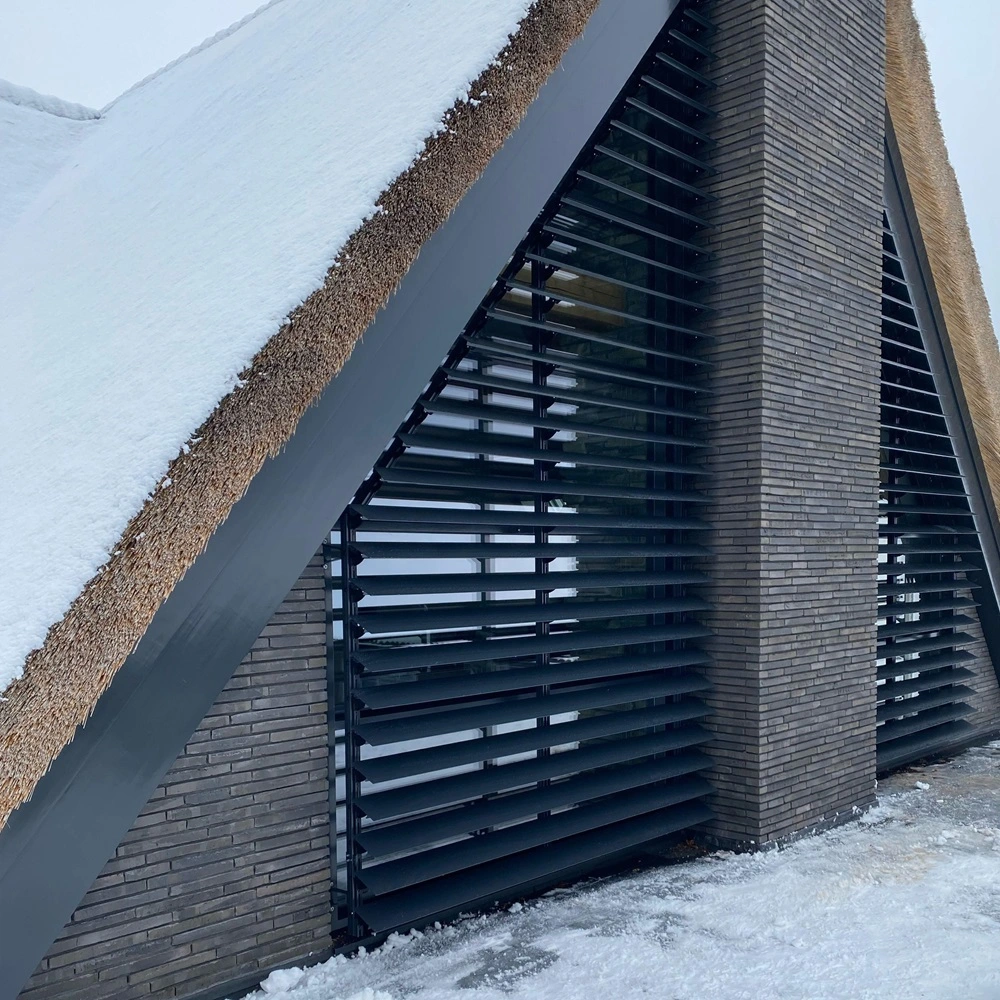 Louvre zonwering op puntgevel van huis met sneeuw op het dak