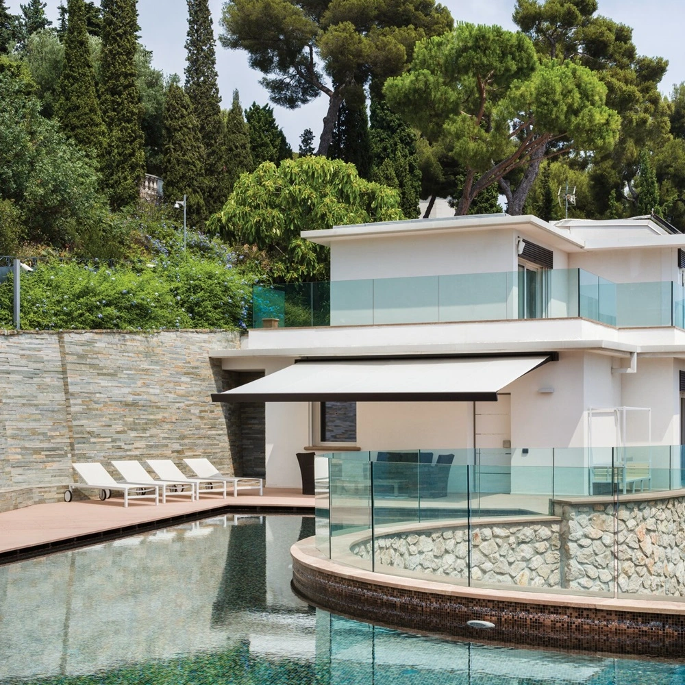 Nodo knikarmscherm over terras met loungestoelen bij zwembad