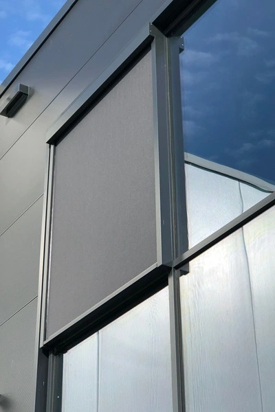 Roma zipscreen F50 geïnstalleerd op grijze gevel met grote glazen ramen Roma zipscreen F50 geïnstalleerd op grijze gevel met grote glazen ramen