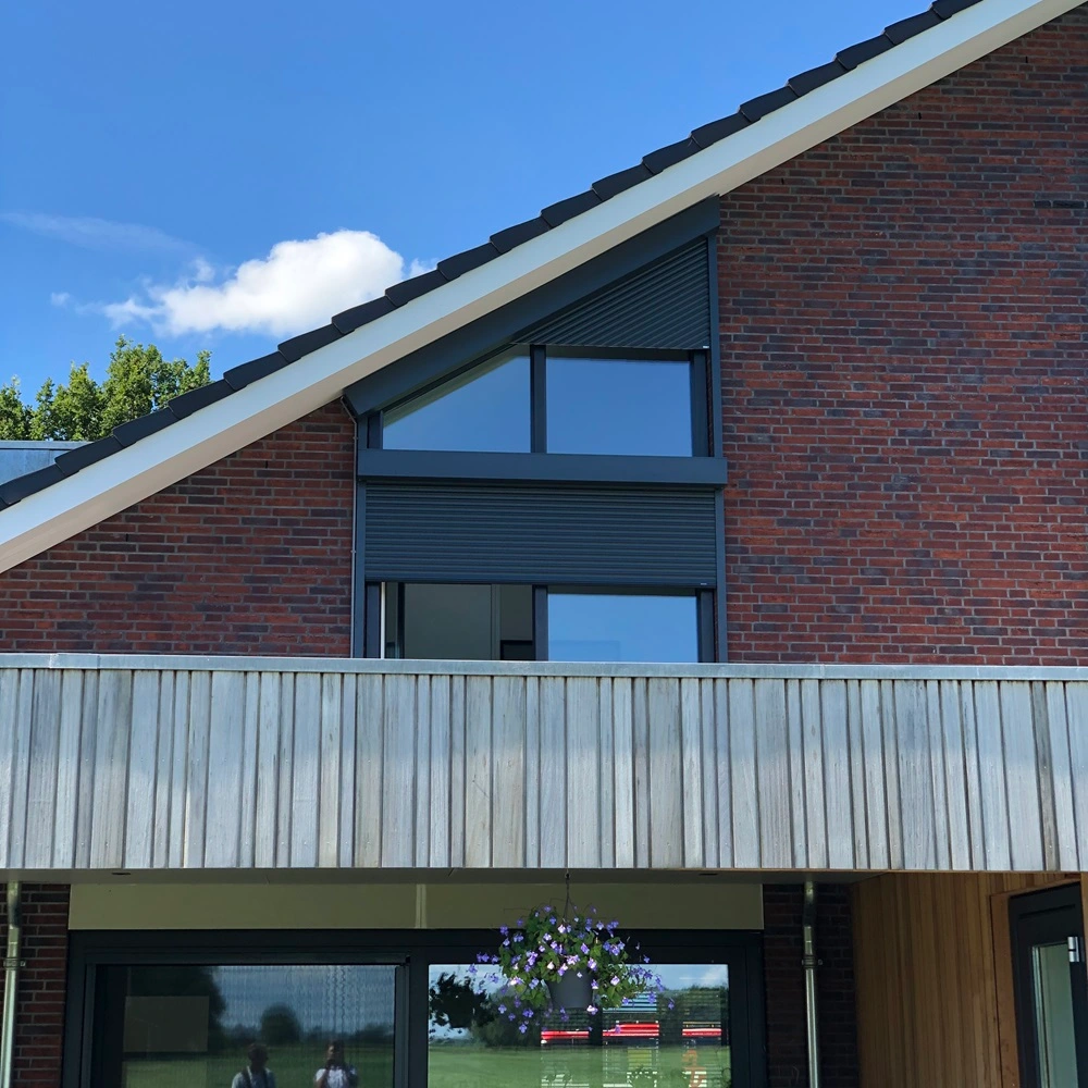 Schuin rolluik op bakstenen woning met houten balkon en glazen ramen
