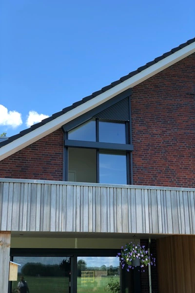 Schuin rolluik op woning met bakstenen gevel en houten balkon Schuin rolluik op woning met bakstenen gevel en houten balkon