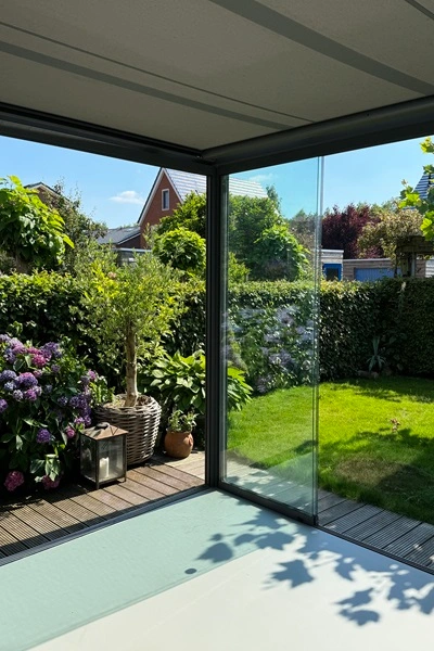 Serrezonwering Sottezza in tuin met glazen schuifwand en groene omgeving Serrezonwering Sottezza in tuin met glazen schuifwand en groene omgeving