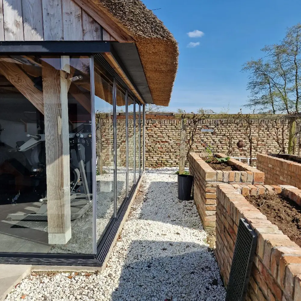 W17 Easy glazen schuifwand rondom houten bijgebouw met bakstenen tuinmuur