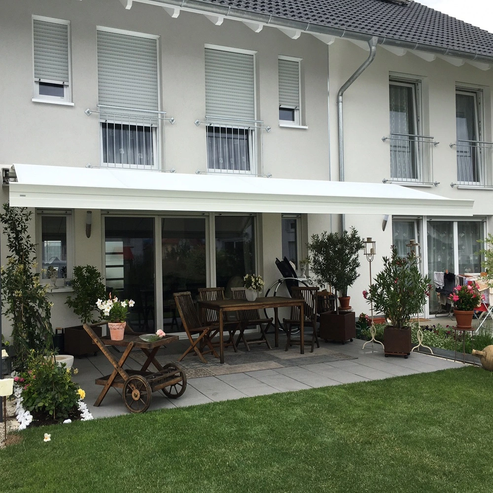 Zon en regenscherm ZRS aan terras van witte woning met groene tuin