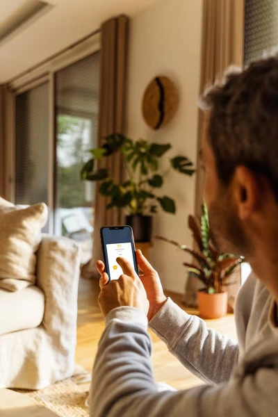 Man gebruikt de Tahoma app voor individuele en groepsbesturing van zonwering Man gebruikt de Tahoma app voor individuele en groepsbesturing van zonwering