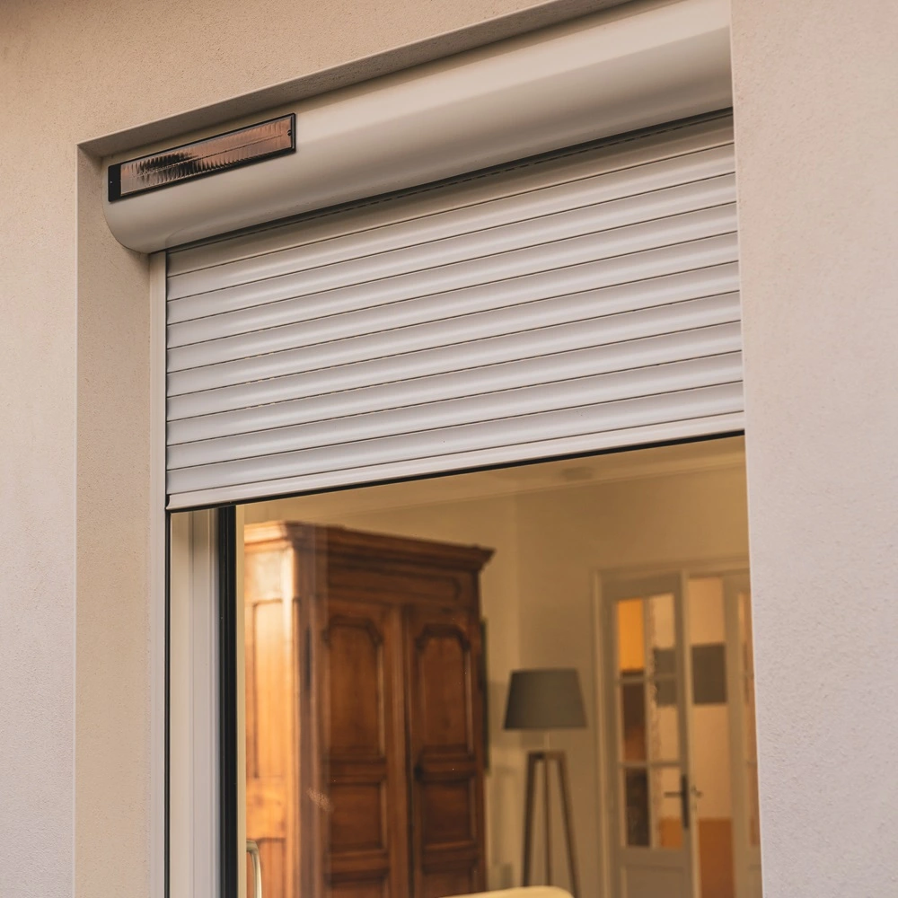 Wit solar rolluik op groot raam met zicht op interieur