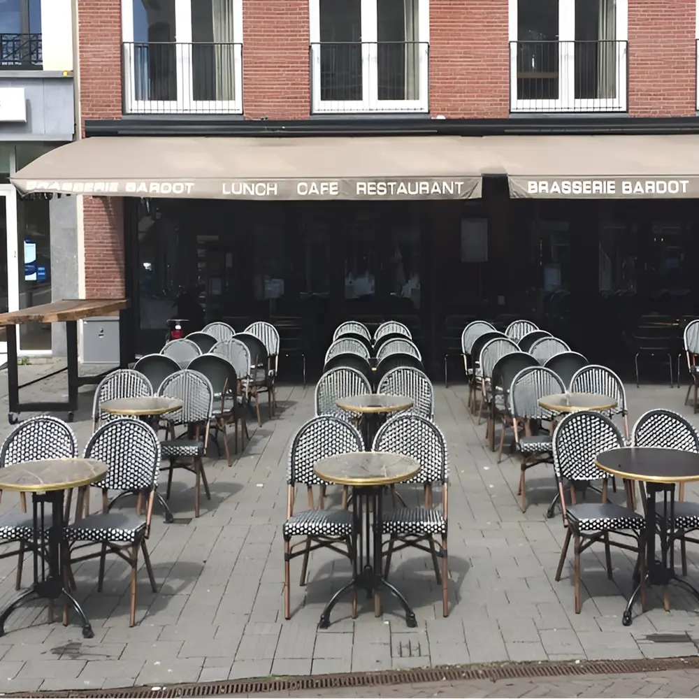 Buitenstoelen en tafels onder schaararmscherm bij Brasserie Bardot
