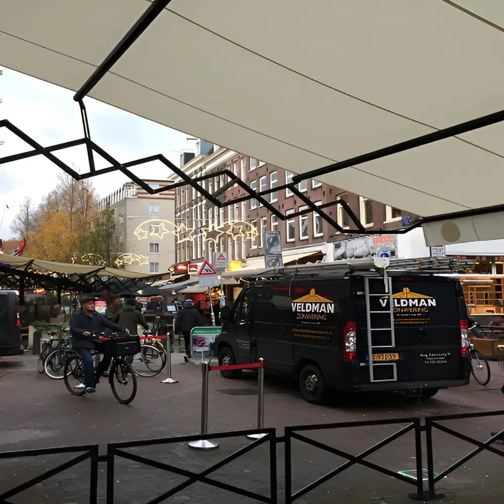 Doek van schaararmscherm gespannen boven terras voor zon en regenwering
