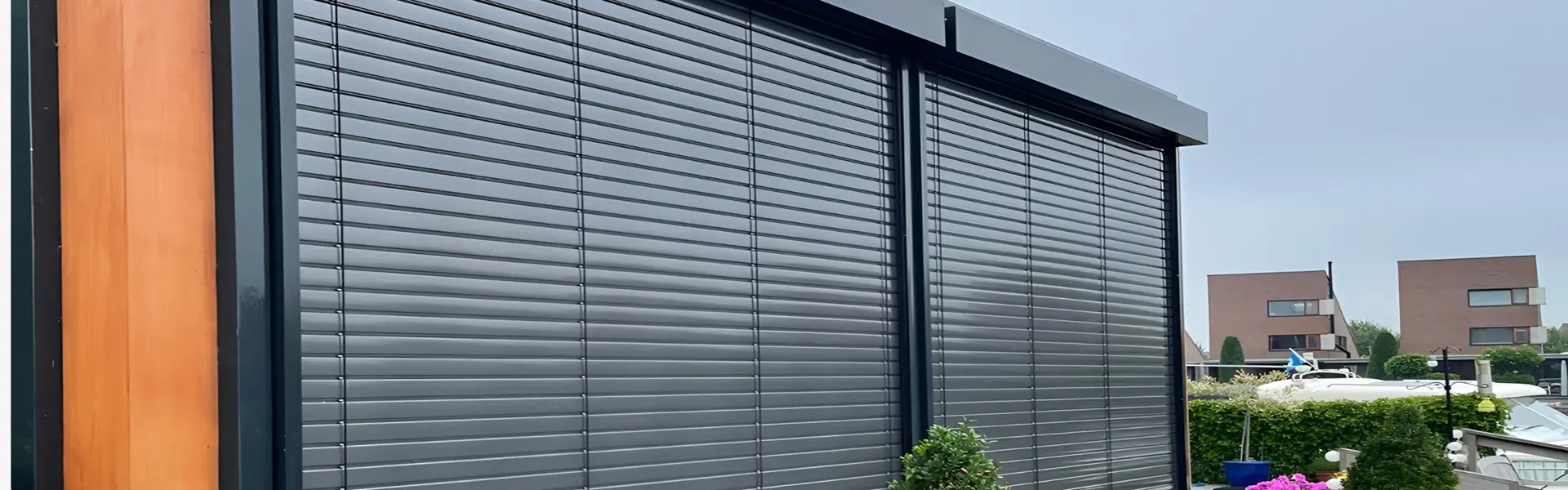 Gesloten buitenjaloezieen met houten geveldetail en uitzicht op woningen