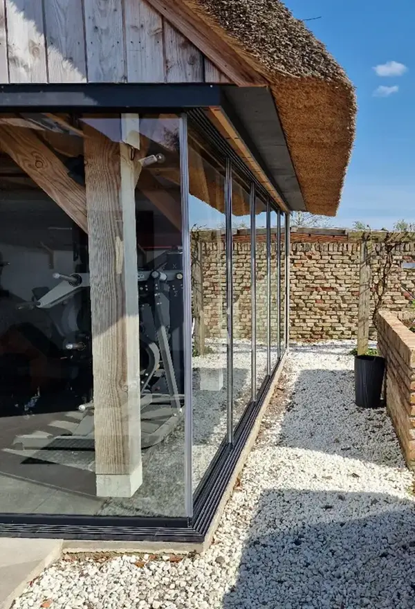 Glazen schuifwanden met houten steunpalen in buitenverblijf