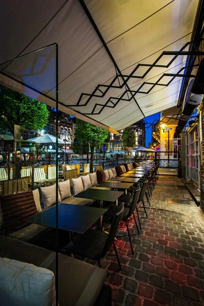 Horecaterras met schaararmscherm ZRS en glazen afscheiding bij avondlicht Horecaterras met schaararmscherm ZRS en glazen afscheiding bij avondlicht