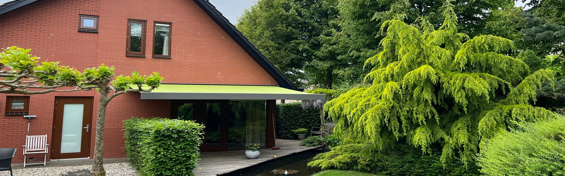 Knikarmscherm aan huis met groene tuin en vijver