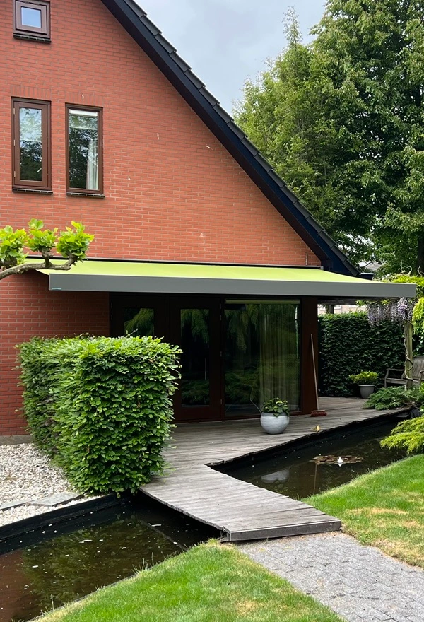 Knikarmscherm aan huis met vijver en tuinpad