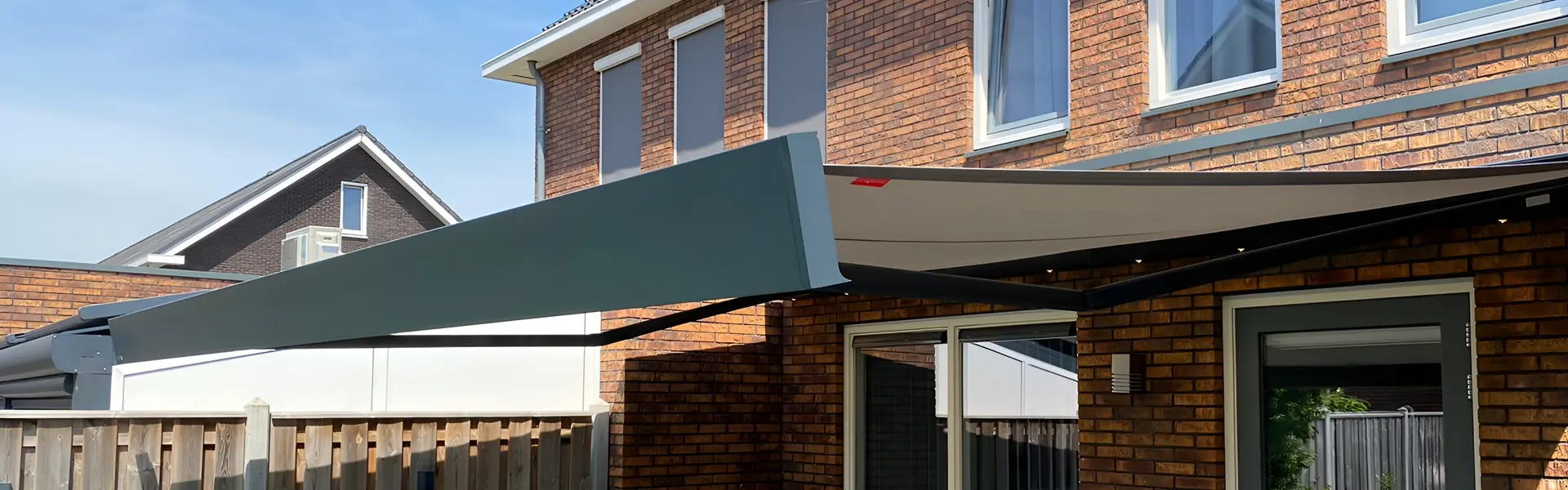 Knikarmscherm boven terras naast raam en schutting
