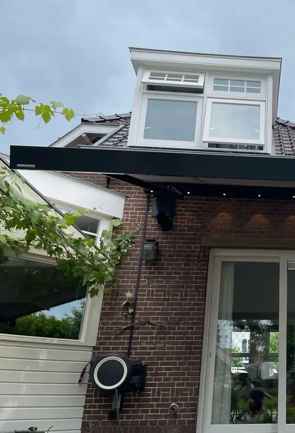 Knikarmscherm met verlichting naast een raam boven schuifdeuren Knikarmscherm met verlichting naast een raam boven schuifdeuren