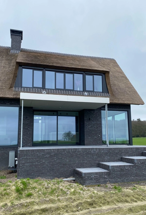 Rieten dakwoning met grote glazen wand en terras in Oudemirdum