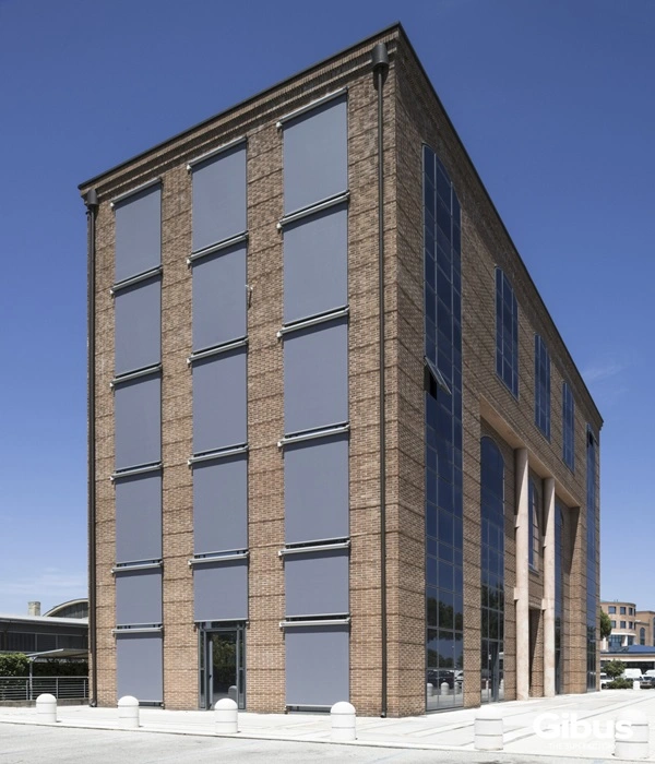 Rode bakstenen muur met grote grijze screens als zonwering