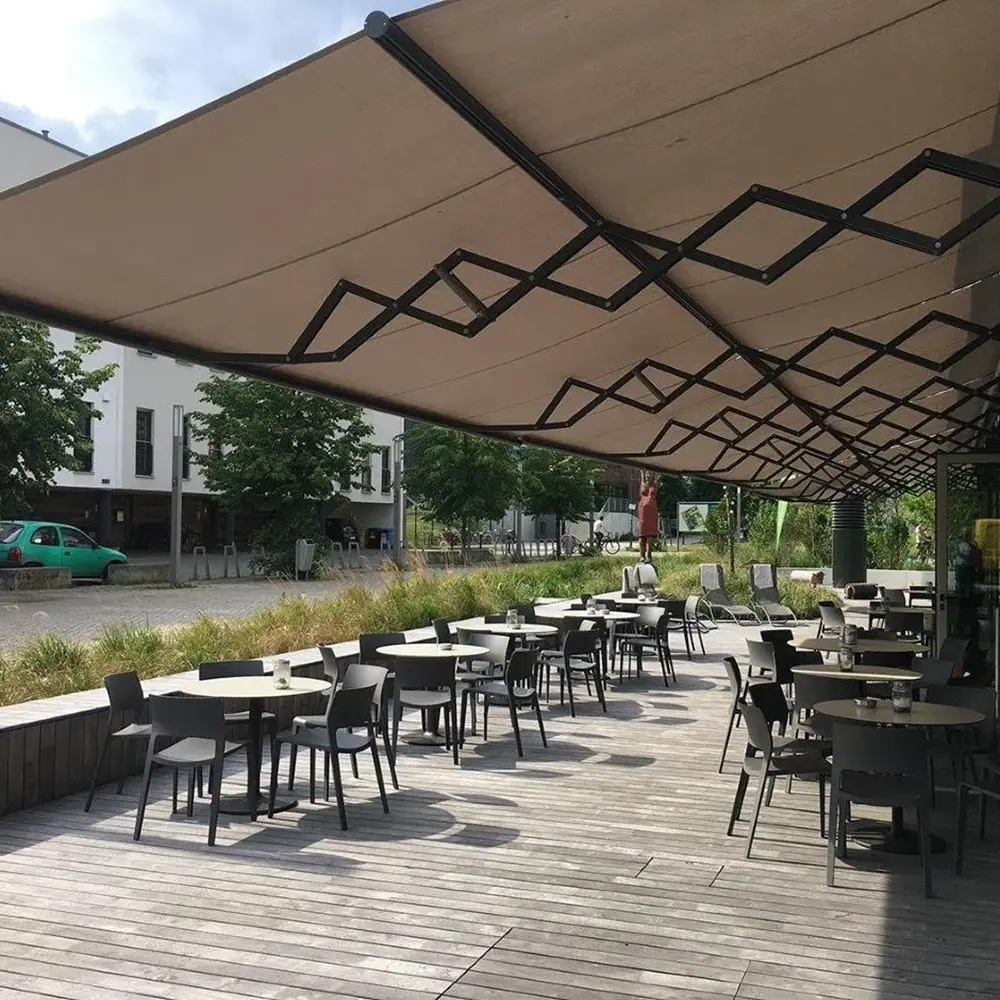 Ruim horecaterras met schaararmscherm en zitplaatsen langs glazen gevel