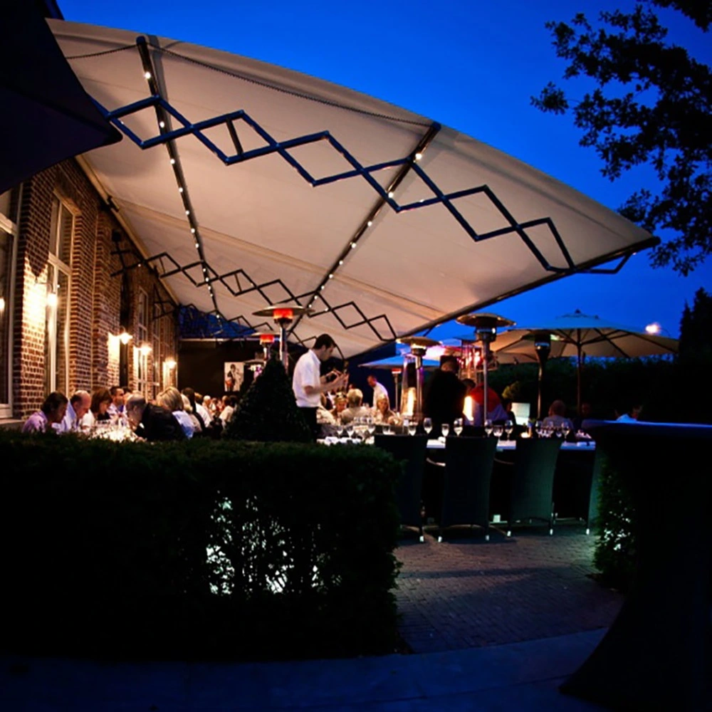 Schaararmscherm XL boven terras bij avond, biedt ruime beschutting voor gasten